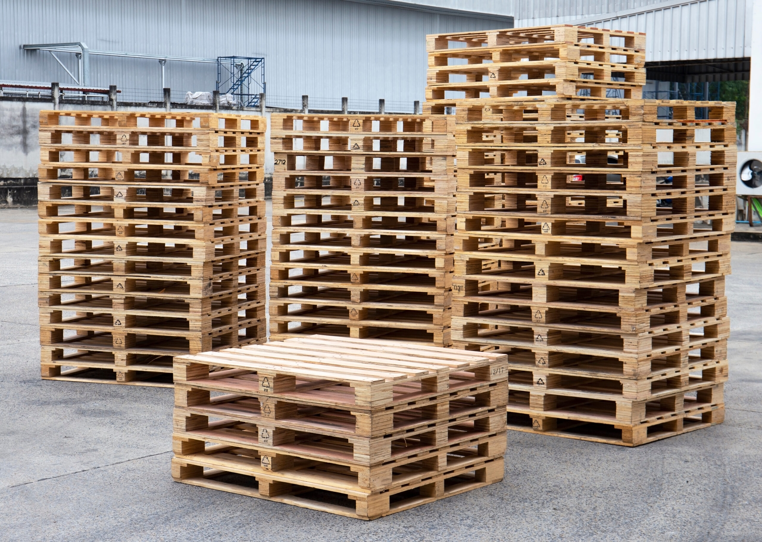 A group of stacked wooden pallets in an industrial warehouse that values pallet maintenance and looks out for signs of mold.