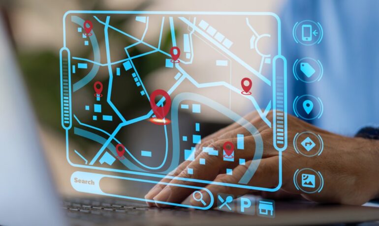 A person places their hand on a laptop keyboard. A map with tracking data and a bar underneath that says "Search' is visible.